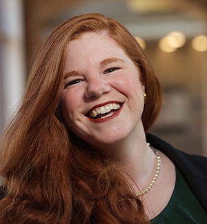 Portrait of smiling woman with long red hair against blurry background. 