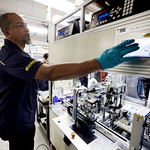 Man in gloves operating a machine in the battery lab. 